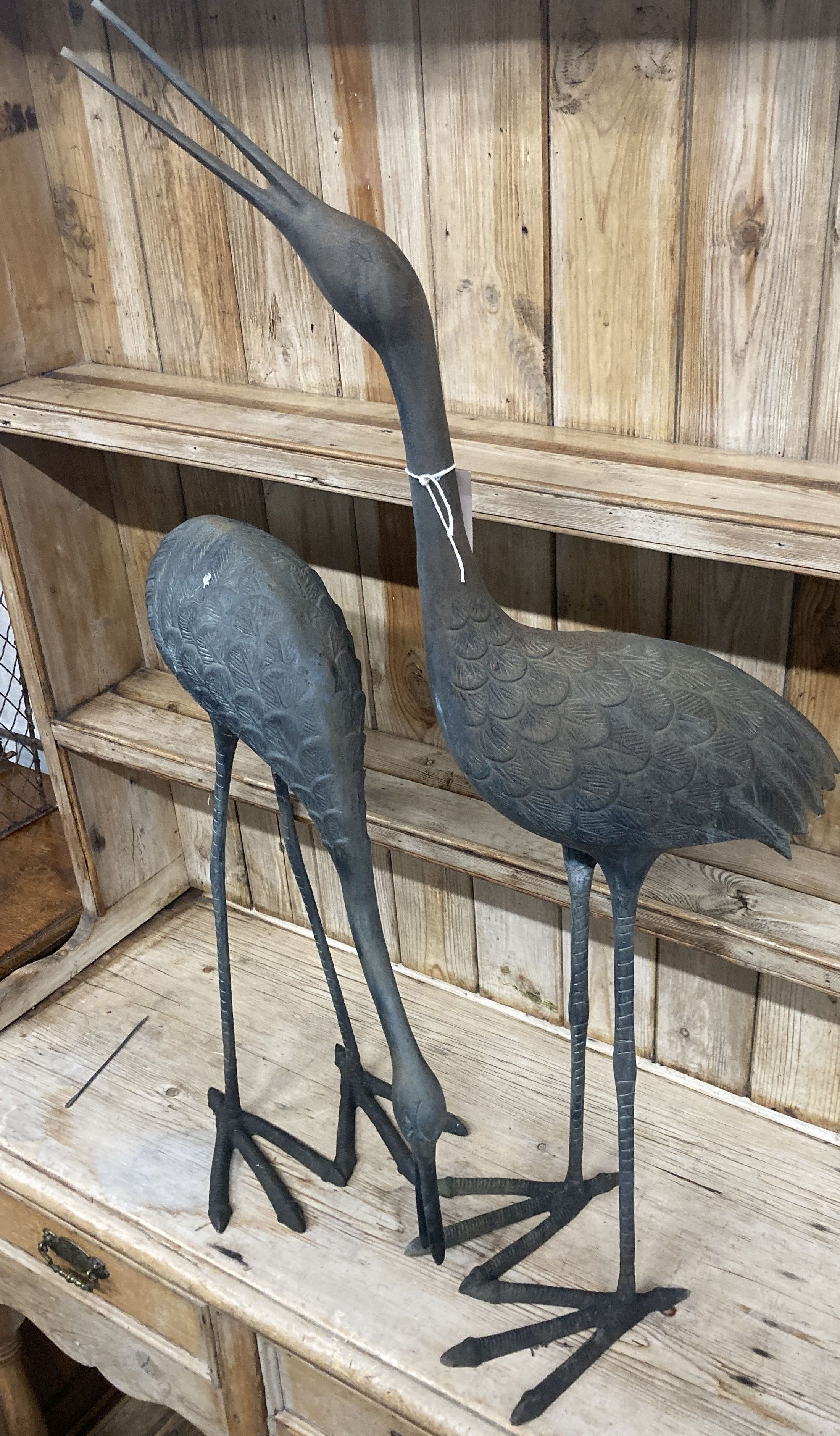 A pair of patinated cast metal garden cranes, larger 91cm high